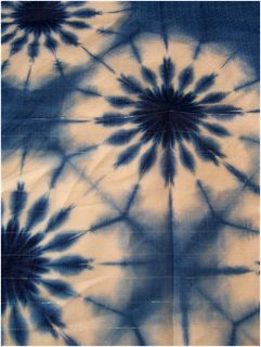 a blue and white tie - dyed fabric with black flowers in the center on it