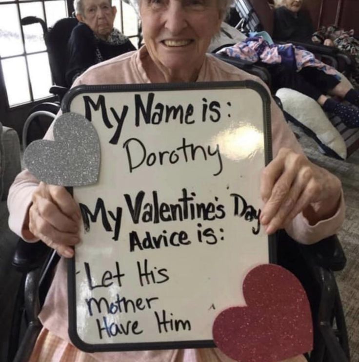 an elderly woman holding up a sign that says, my name is drotny my valentine's day advice is let his mother have him