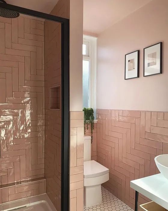 a bathroom with pink walls and tile flooring next to a white sink, toilet and shower