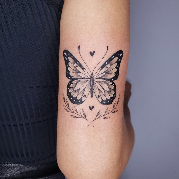 a woman's arm with a butterfly tattoo on the left side of her arm