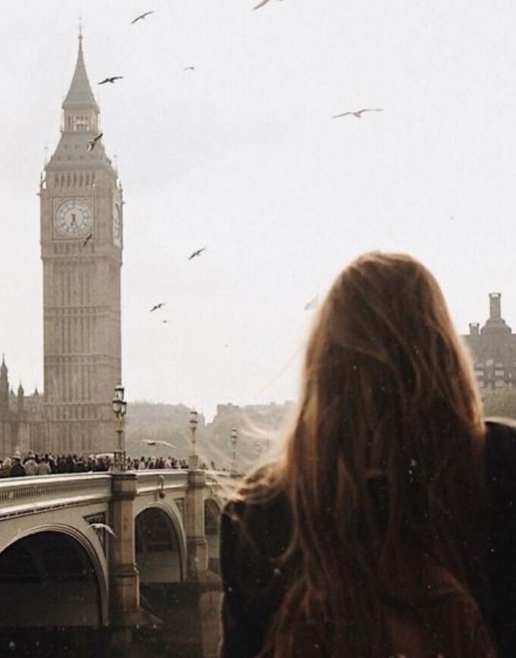 there is a woman that is looking at the big ben clock tower