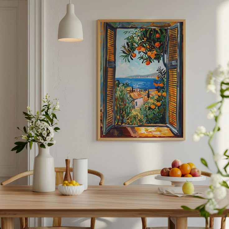 a painting hangs on the wall above a table with fruit and flowers in vases