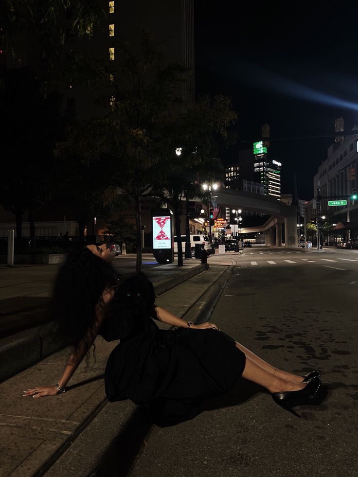 a woman laying on the side of a road at night with her legs spread out