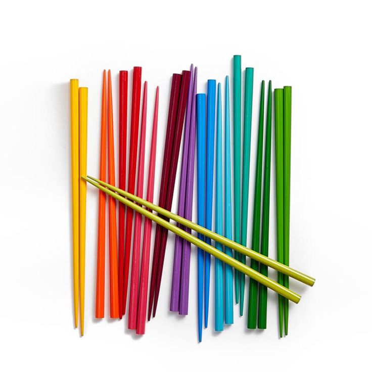 several different colored straws are lined up on a white surface with one yellow stick sticking out of it