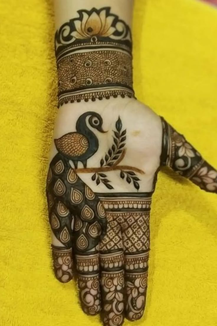 henna tattoo on the palm of a woman's hand with peacocks and leaves