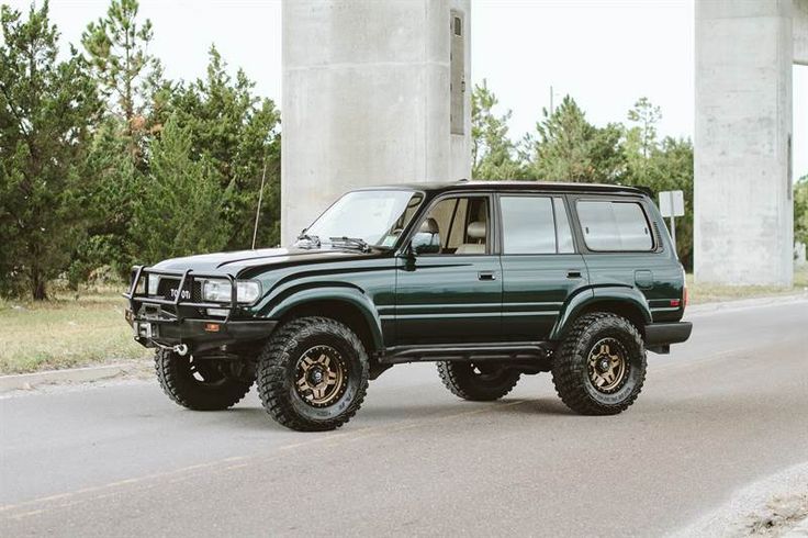 a green suv is parked on the side of the road