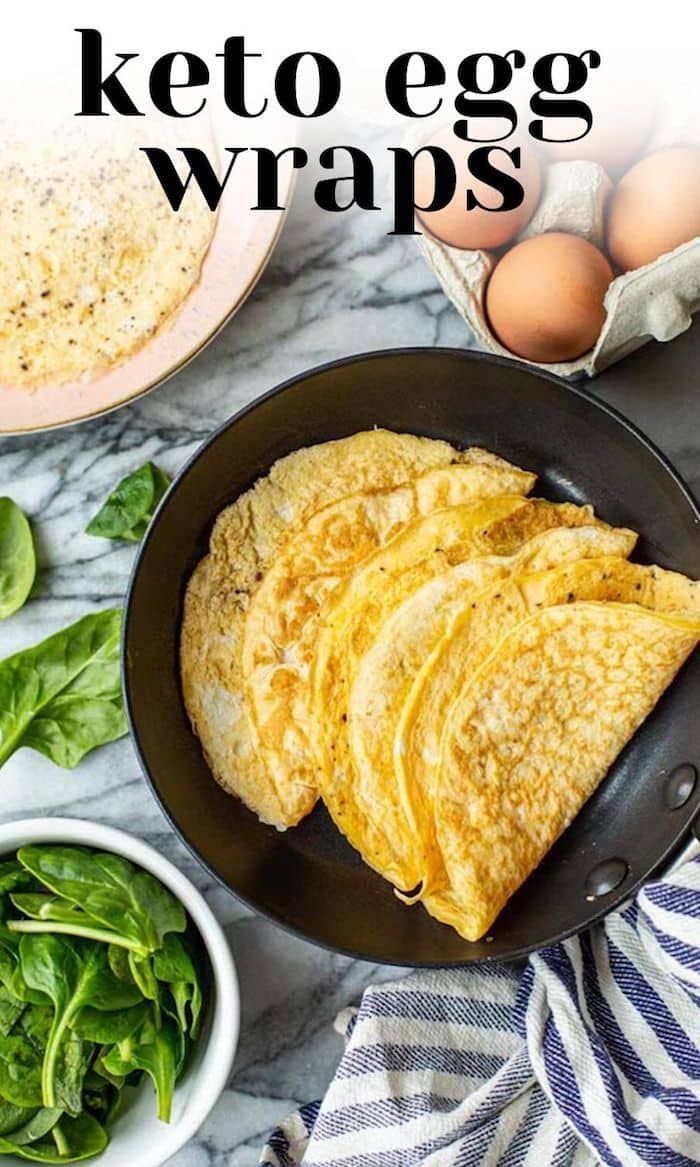 keto egg wraps in a skillet with spinach and eggs on the side