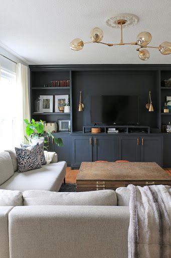 a living room filled with furniture and a flat screen tv mounted on a wall next to a window