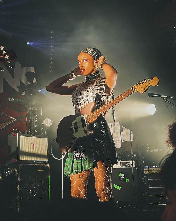 a woman standing on top of a stage with a guitar in her hand and wearing fishnet stockings