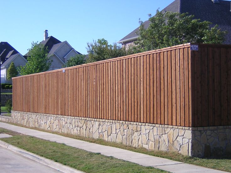 a large wooden fence next to a sidewalk