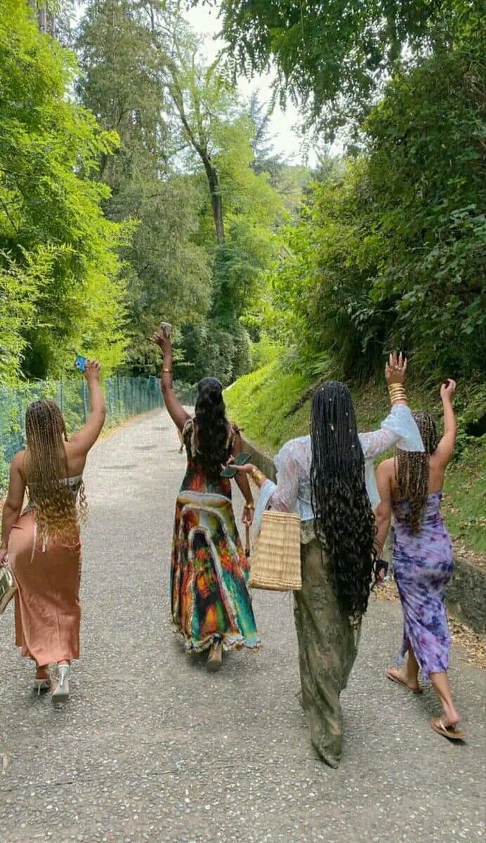 three women walking down a road with their arms in the air