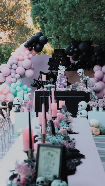 an outdoor party with balloons, candles and decorations on the long table in front of it