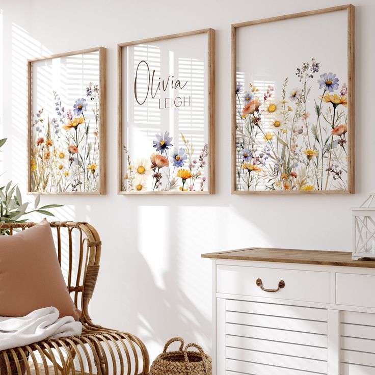 three framed art prints hanging on the wall above a wicker chair in a white room