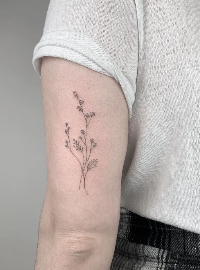 a woman's arm with a small flower tattoo on the left side of her arm