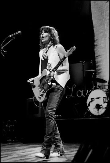 a woman standing on stage with a guitar