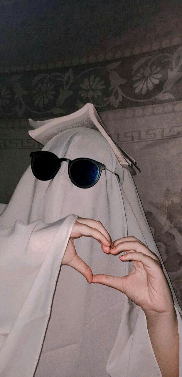 a person wearing sunglasses making a heart shape with their hands