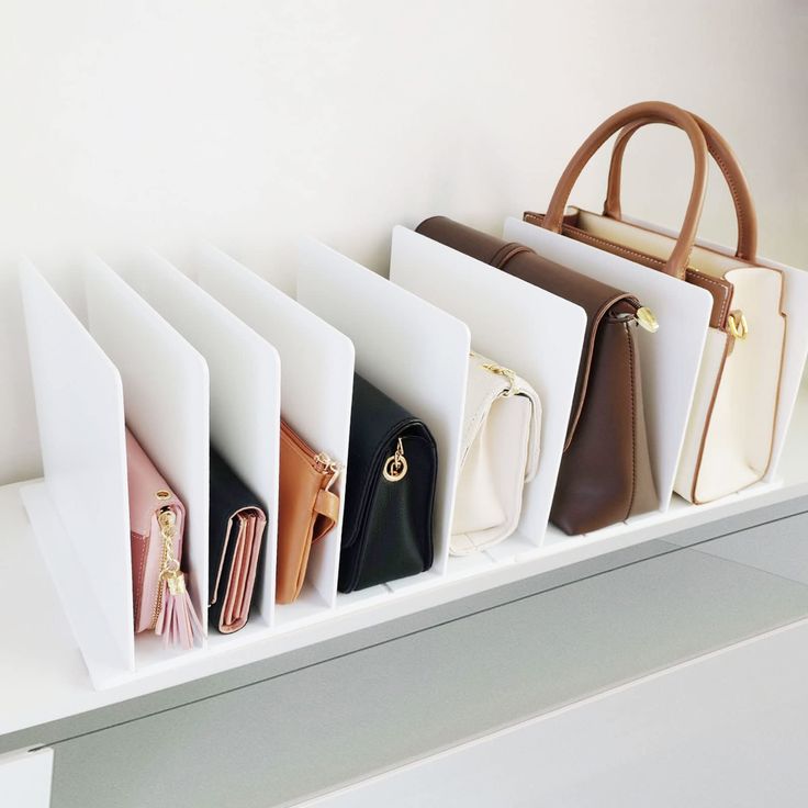 five purses are lined up on a shelf in front of a white wall,