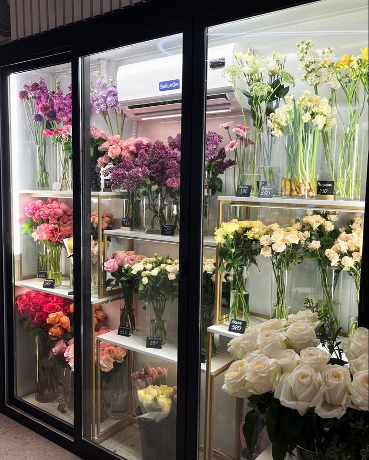 flowers in vases on display behind glass doors at a florist shop or flower shop