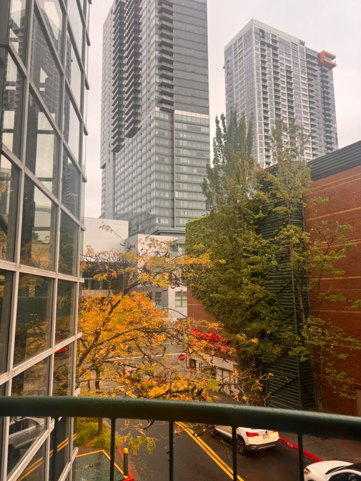 the view from an apartment balcony looking down at tall buildings and trees in the distance