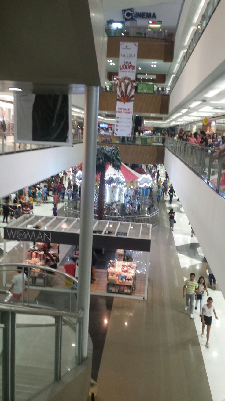 an indoor mall with people walking around and shopping on the escalator in front of them