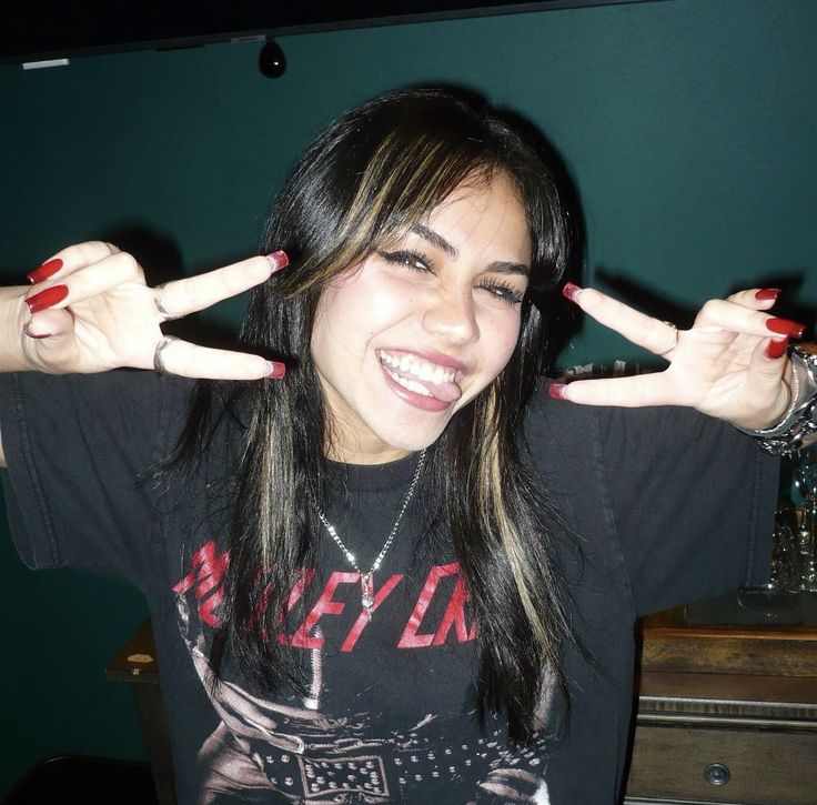 a woman with long black hair and red nails holding her hands up in the air