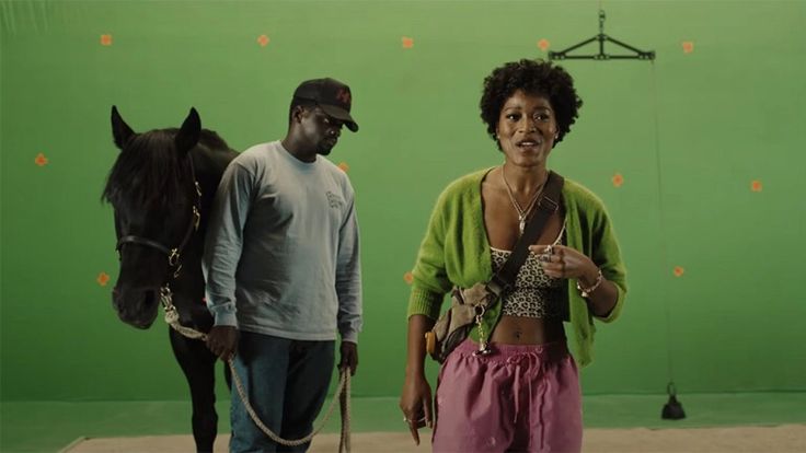 two people standing in front of a green screen with a horse on the other side