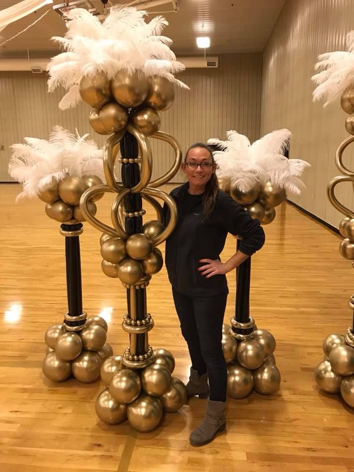 a woman standing in front of some gold and white decorations on top of a hard wood floor