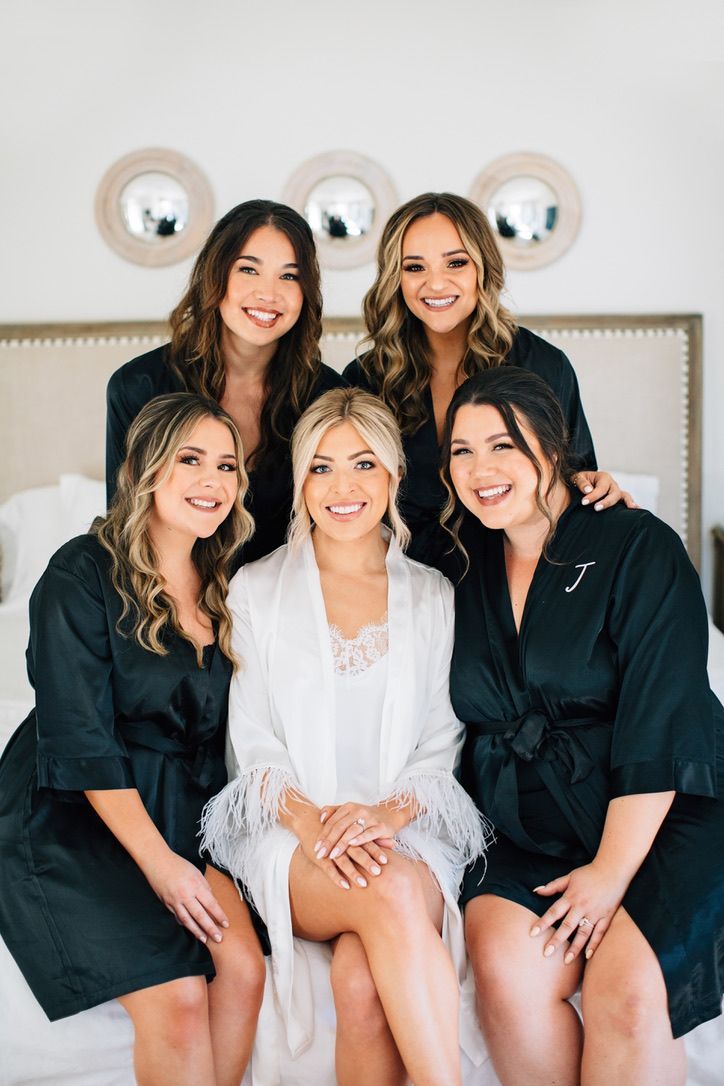 the bridesmaids are all dressed in black robes and posing for a photo on their bed