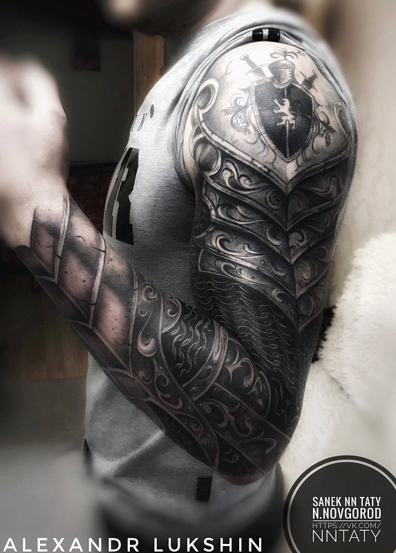 a man with tattoos on his arm and shoulder is holding onto an object in front of him