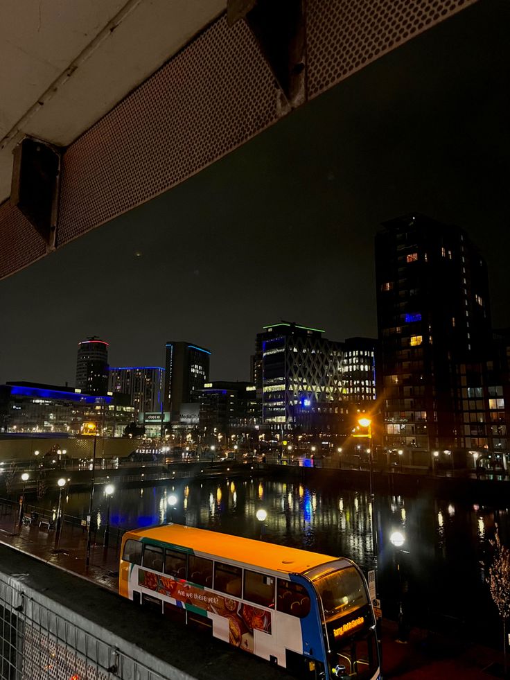 a bus parked on the side of a road next to a body of water at night