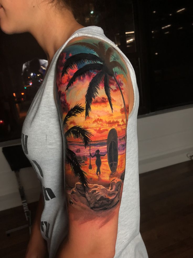 a man with a surfboard and palm trees on his arm is standing in front of the sunset