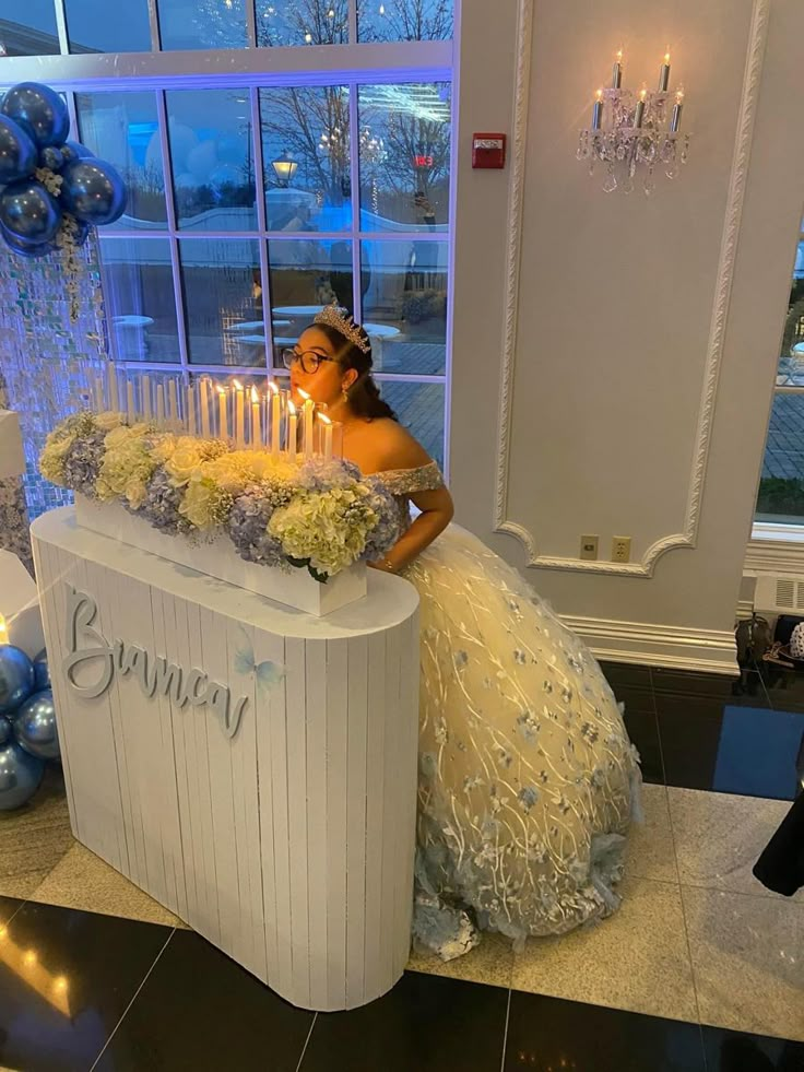 a woman in a wedding dress standing next to a large cake with candles on it