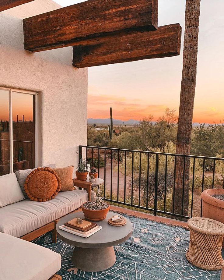 an outdoor living area with couches, tables and chairs on the patio at sunset