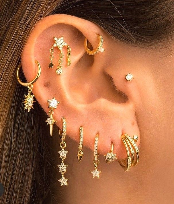 a close up of a person's ear with five different types of piercings