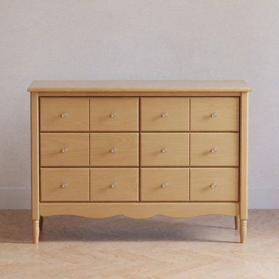 a wooden dresser sitting on top of a hard wood floor next to a white wall