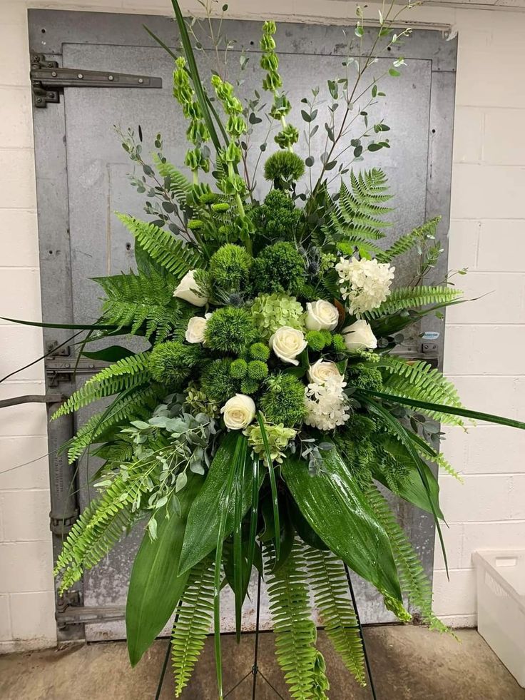 an arrangement of white flowers and greenery in a vase