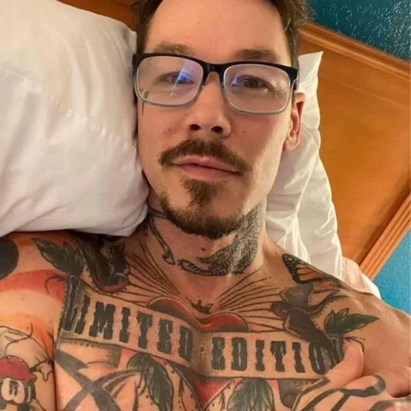 a man with tattoos on his chest laying in bed