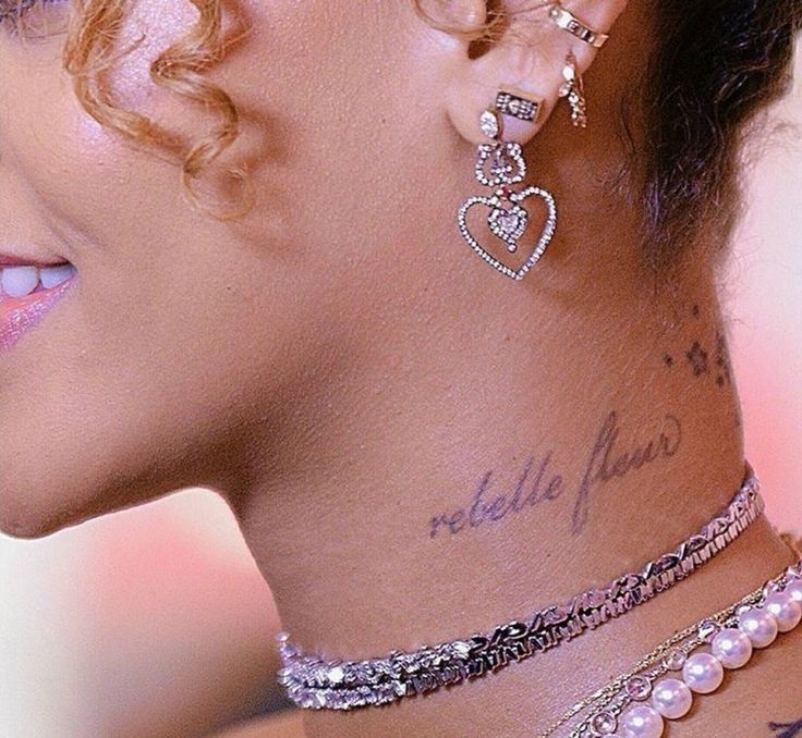 the back of a woman's head with tattoos on her neck and behind her ear