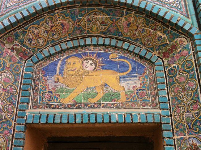 an ornate doorway with a lion painted on the front and side wall, in blue tiles