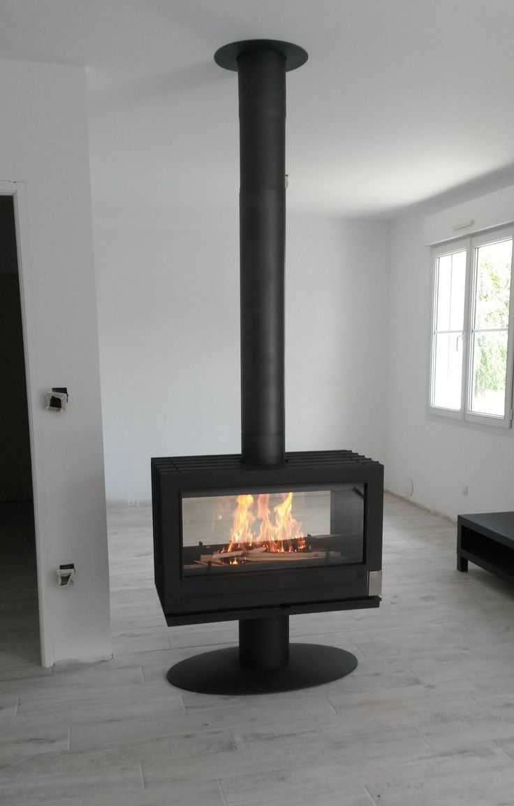 a fire place in the middle of a room with white walls and wood flooring