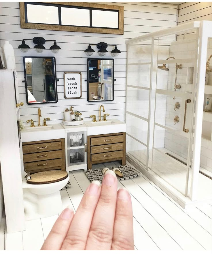 a person's hand is pointing at a bathroom with two sinks and a shower