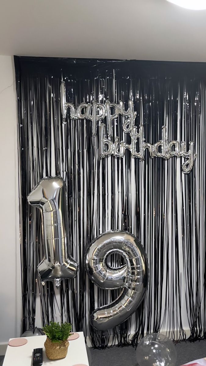 a black and white birthday backdrop with silver foil balloons, streamers and the number six