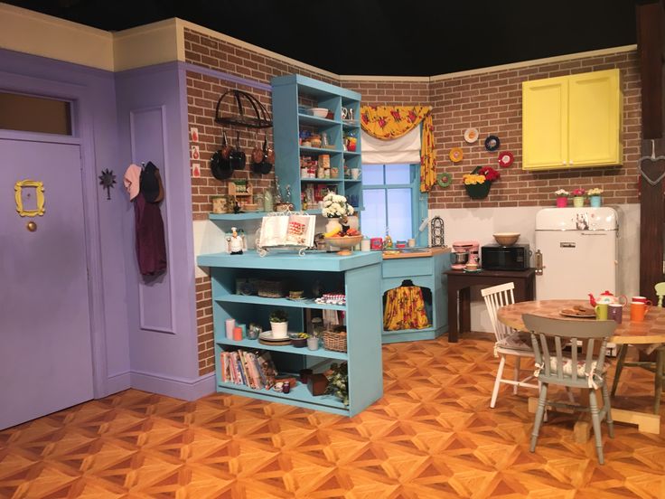 a dollhouse kitchen and dining room with blue cabinets, purple walls and wooden floors