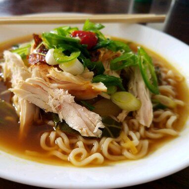 a white plate topped with noodles, meat and veggies next to chopsticks