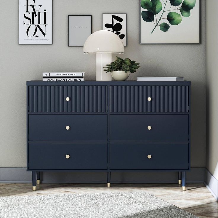 a blue dresser sitting in a room next to a lamp and pictures on the wall