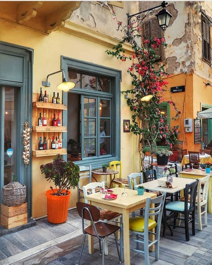 an outdoor dining area with tables and chairs, potted plants on the outside wall