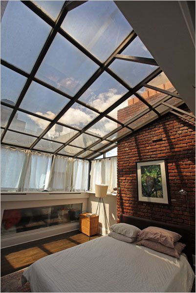 a bed sitting under a glass roof in a bedroom