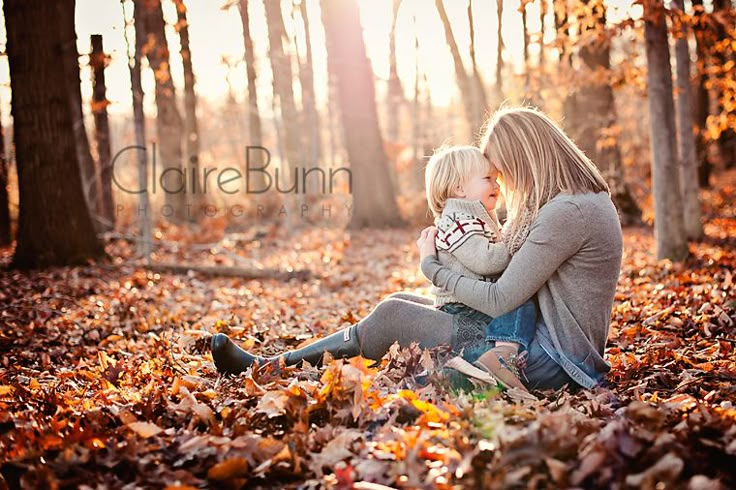 a mother and her child are sitting in the leaves