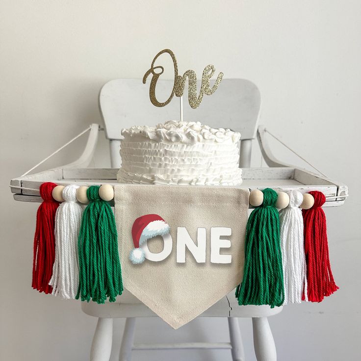 a one year old birthday cake on top of a white chair with tassels