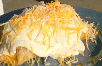 a blue plate topped with food covered in cheese and sour crumbled toppings